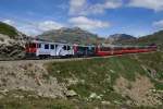 Unterhalb der Staumauer des Lago Bianco bremsen die beiden Werbetriebwagen ABe 4/4 III 51 und ABe 4/4 III 52 den Bernina-Express 973 Richtung Alp Grm.
