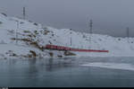 Regionalzug 1644 aus Tirano fährt am 20. Dezember 2016 kurz vor Ospizio Bernina dem Ufer des gefrorenen Lago Bianco entlang in Richtung St. Moritz.