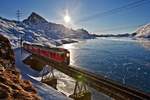 Der RhB Triebzug ABe 4/4 III Nr.51  Poschiavo  und Nr. 52  Brusio  fahren mit einem R am schwarzgefrorenen Lago Bianco entlang.Nild vom 28.12.2016 