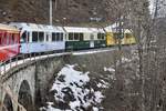 Der  Ahnenzug  ABe 8/12 3514 als Regio nach Arosa am 26.12.23 auf einem Viadukt zwischen St. Peter-Molinis und Peist.