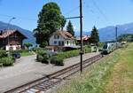 Bahnhof Faulensee: Nachdem gerade ein ICE aus Berlin durchgefahren ist kommt nun der Lokalzug (BLS MUTZ 028) von Interlaken her durch die hübsche Bahnhofsanlage am Thunersee (heute eine Ferienwohnung). 