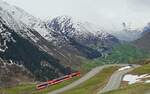 Unterhalb der Oberalpstraße ist der ABDeh 4/8 2028 der Matterhorn-Gotthard-Bahn am 06.05.2024 kurz vor der Station Nätschen nach Disentis unterwegs, im Hintergrund das einige hundert Meter tiefer liegende Urserental