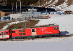 Die Lok des Regionalzuges von Andermatt nach Disentis befährt die Zahnstangenweiche in der Station Nätschen (1825 müM). Andermatt, 13.2.2023