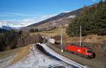 1016 022 befördert die ROLA 53337 (Wörgl - Brennersee) bei Mühlbachl den Berg hinauf. Im Hintergrund thront die schneebedeckte Nordkette über Innsbruck. (31.01.2020)