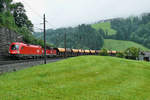Ein schwerer Güterzug mit der 1016 039 in Front kämpft sich bei Unterwindau die Kehren hoch in Richtung Brixen.