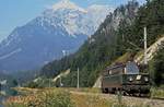 Am 25.08.1980 fährt 1042.37 als Lz durch das Gesäuse an der aufgestauten Enns entlang, im Hintergrund der Große Buchstein (2.224 m)