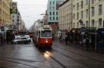 Wien Wiener Linien: An einem trüben Regentag im Februar 2016 nähert sich eine E2+c5-Garnitur (E2 4084 + c5) auf der SL 67 der Haltestelle Reumannplatz (im 10.