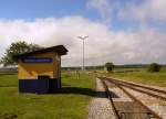 Die Haltestelle Raiding Lackendorf im August 2010 bei Km 19,0. Im Hintergrund auf Höhe der querenden Straße sieht man einen Bahnschranken  mal anders  nicht über die Straße sondern über die Geleise gerichtet. Grund ist, die Draisinenfahrer auf die Gefahr der Straße aufmerksam zu machen. Ein Stück dahinter sieht man eine Draisine in Richtung Oberpullendorf fahren.