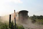 Zuerst habe ich mich �ber die Staubwolke ge�rgert, andererseits zeigt das Bild aber wie sehr Eisenbahnfotographie eine gesundheitliche Belastung sein kann (:-). - LOC 489 (Surat Thani - Khiri Ratthanikhom) mit dem บชส. 277 (บชส. =BTC./Bogie Third Class Carriage) als letztes Fahrzeug hat am 18.M�rz 2026 die unbefestigte EK mit einer Bezirkstrasse passiert.