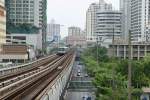 Ein Skytrain-Triebwagen fährt hoch über der Thanon Phaya Thai von der BTS Victory Monument Station (N3) zur BTS Phaya Thai Station (N2).