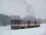 Bei dichtem Schneetreiben verlässt die Sandwichgarnitur bestehend aus den drei  Brotbüchsen : Triebwagen 810 559 - Beiwagen - Triebwagen 810 145 den 782 m hoch gelegenen Bahnhof Moldava v