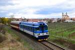 Die 854 202-er Triebwagen fährt mit einem Beiwagen von Břeclav nach Znojmo zwischen Valtice Mesto und Valtice. Im Hintergrund ist die Kirche Maria Himmelfahrt zu sehen.
Valtice 01.04.2023.