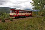 810 077-8 kommt als Os 18108 von Strakonice nach Volary bei Zátoň vorbei.über dem Triebwagen ist der an diesem Tage leicht in Wolken verhüllte Berg Boubín erkennbar.Bild vom