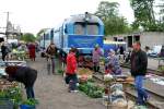 Salat, Gurken, Kartoffeln und die TU2-034 der Schmalspurbahn in Vynohradiv. Das liegt im Südwesten der Ukraine nahe der Kaparten. Die Schmalspurbahn verbindet einige Orte welche mit dem Auto bzw Bus kaum zu erreichen sind. Leider fährt die Bahn aus Kostengründen nur noch 3 mal pro Woche mit eine stark abgespecktem Streckennetz. Meinen Recherchen zufolge sind noch 2 TU2 fahrtüchtig, auch mit Hilfe eines Schweizer Eisenbahnfreunde Club, welcher seine Einnahmen für einen Kalenderverkauf für die Reparaturen der Loks spendete. Leider steckt sich die Regierung der Ukraine das meiste Geld selbst in die Tasche und das Volk hat das Nachsehen.
... Das interessante in Vynohradiv ist das dort der Basar direkt auf dem Gleisbett stattfindet. Auch die Lok rangiert für die Rückfahrt mitten durch die Stande der Händler. In Europa kaum vorstellbar. Klappt aber ganz gut ohne grosse Zwischenfälle wie ich dort beobachten konnte.
Bild am 30.04.2015 in Vynohradiv.