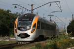 Hyundai Rotem HRCS2-001 rauscht über den Bahnübergang in Smila am 14.08.2015.
Das ist auch ein Prozedur für sich. Es bimmelt eine Glocke ewig lang bevor der Zug überhaupt im Bahnhof in Sicht ist.
Jetzt spurtet die Schrankenwärterin aus ihrem Häuschen und rennt zur ersten Schranke. Dort wird die Schranke herunter gelassen Zusätzlich noch eine Art Schlagbaum Sperre, welche sogar mit einem Vorhängeschloss abgesperrt wird. , Dann das selbe nochmal auf der anderen Seite. Die Autos müssen so ca 10 Minuten warten. Dann kommt der Zug. Zuvor wird nochmal in eine kleine Pfeife getrötet. erinnert an den kölschen Karneval, würde ich sagen. Die grüne Kelle wird vorschriftsmässig in die Luft gehalten. Nachdem der Zug durch ist, jetzt schnell alles wieder aufsperren, im Laufschritt. Fitnesstraining ist hier in der Stellenbeschreibung bestimmt mit dabei.