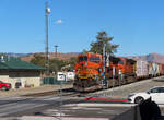 Gemischter BNSF-Güterzug passiert mitten im Städtchen Tehachapi einen Bahnübergang und fährt anschliessend westwärts den Pass hinunter in Richtung Bakersfield.