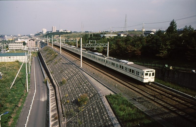 Tokyo S-Bahn,  Feinverteilerbahnen : Keiô-Konzern. Im Bild erkennbar ist die Rolle dieser Bahnen bei der Erschliessung von Neubausiedlungen.Zug der Serie 6000 (1972-1991 gebaut,304 Wagen,2-,4-,5- und 8-Wagenzüge,die je nach Bedarf zusammengefügt werden). Diese Züge fahren auch auf die Städtische U-Bahn Tokyo, Shinjuku-Linie, ein und unterqueren dabei ganz Tokyo. Bild: Endwagen 6787, Minami Ôsawa, 14.Oktober 1994. 