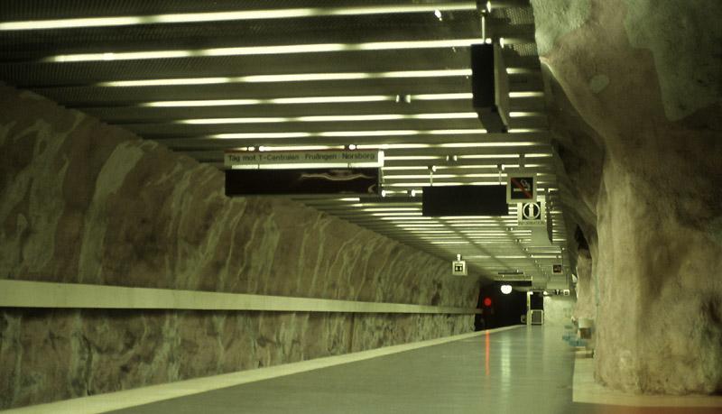 Tunelbana Stockholm: Die Station  Mrby Centrum  (1975)ist eine typische in den Fels gehauene Station. Die Felswnde wurden lediglich mit einer dnnen Schicht Spritzbeton berzogen und dann knstlerisch gestaltet. Es gibt 28 Stationen solcher Bauart, neuere bestehen aus eine Bahnsteighalle, whrend die lteren aus zwei durch Querschlge mit einander verbundenen Bahnsteigtunnelrhren bestehen. Die U-Bahn Stockholm gehrt damit wohl zu den schnsten Metros weltweit. Scan vom Dia, 1990 (Matthias)