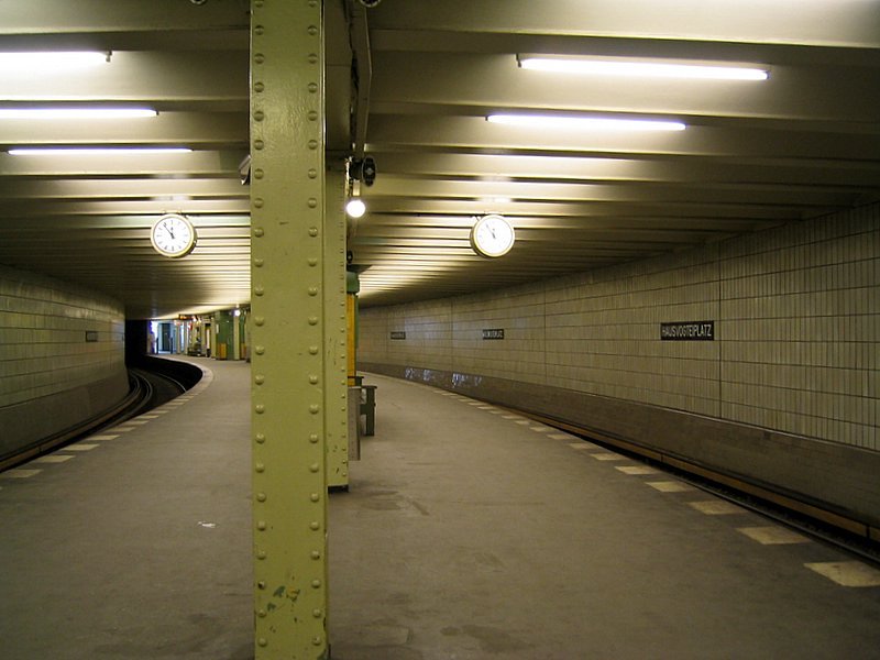U-Bahnhof Hausvogteiplatz: Entwurf 1908 durch Grenander, wie Stadtmitte sandfarbene Kacheln mit typischen Stationsschild. Bahnhof liegt in einer Kurve, sodass die Kr�mmung betr�chtlich ist. Im Krieg weitgehend zerst�rt, nur noch die schmiedeeiserne Umwehrung des Westausgangs ist erhalten. Der Name stammt vom einstigen Untersuchungsgf�ngnis des Hofgerichts, der Hausvogtei.