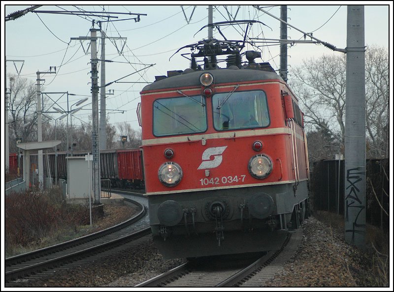 Und wieder eine 42er mit Altlack. 1042 034 mit einem Gterzug am 9.12.2006 bei der Durchfahrt der Stadion Lobau in Wien.