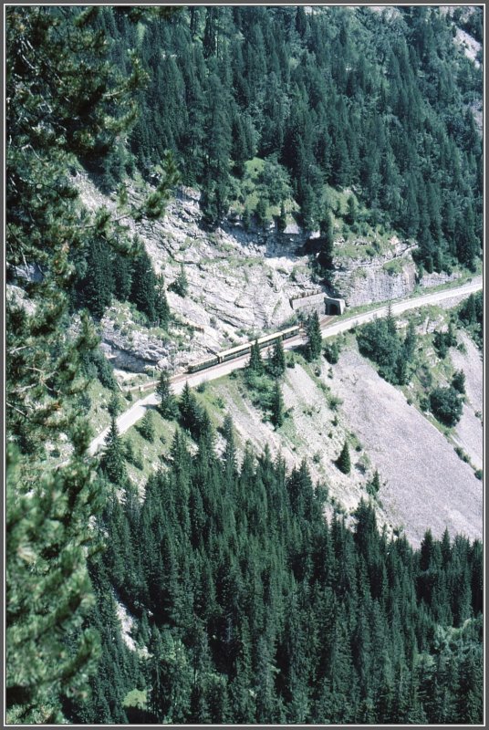 Unterhalb Bergn verluft die Albulastrecke kurze Zeit zwischen zwei Tunnels parallel zur Strasse. Ein usserst kurzer A/B/D-Zug mit einer Ge 6/6 II fhrt Richtung Filisur. (Archiv 08/82)