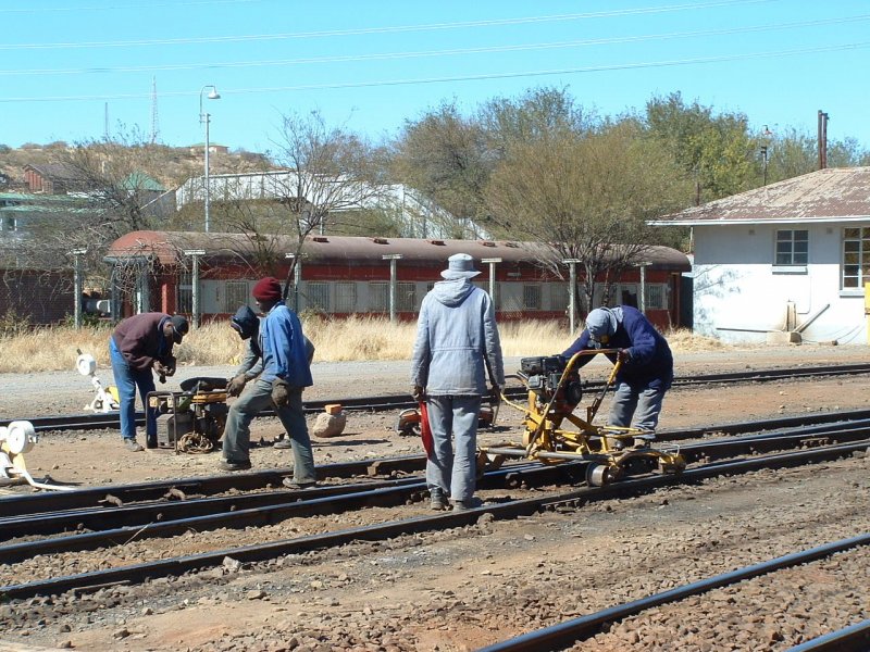 Unterhaltsarbeiten an einer Weiche der Einfahrgruppe zum Depot Windhoek. Im Hintergrund ist das Dienstgebude des Depots Windhoek zu erkennen. Mrz 2006.