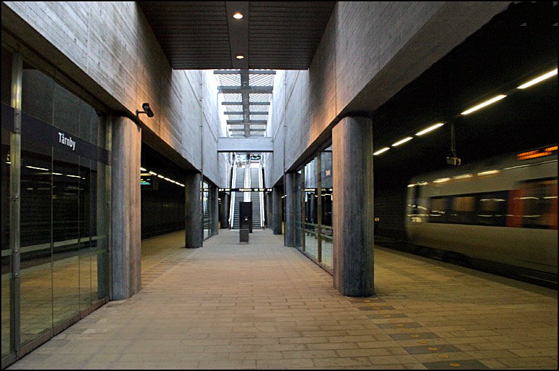 Unterirdischer Bahnhof  Tarnby  an der Øresundbahn. Rechts ist ein Øresundexpress-Triebwagen zu erkennen. Der Streckenabschnitt bis zum Flughafen Kopenhagen wurde 1998 fertiggestellt, die Verbindung über den Øresund folgt zwei Jahre später. Die Sichtbetonarchitekur hat durchaus ihre Reize. Zwischen den eher dunklen Gleisbereichen findet sich ein Bahnsteigmitte ein langgezogene Öffnung mit den Zugangsanlagen, durch die Tageslicht auf die Bahnsteigebene fällt. Es entsteht eine schöne Lichtwirkung. 

27.08.2006 (M)