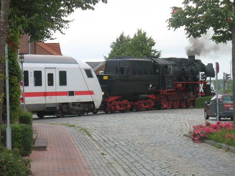 Unterschiedlicher knnen Bahnepochen nicht aufeinander prallen. Die 52 8079-7 zieht den Kurswagen eines IC durch ein Bahnbergang in Niebll (23.07.2008).