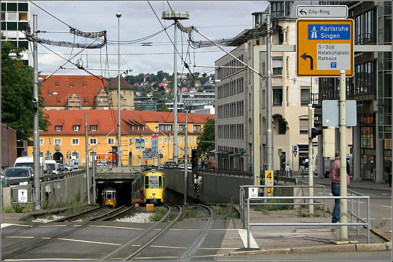 Untertunnelte Innenstadt -

Stuttgart war nach Berlin und Hamburg die erste Stadt, die nach dem Zweiten Weltkrieg begann Tunnelstrecken für den städtischen Nahverkehr zu bauen und die erste die solche Bauwerke für die Straßenbahn erstellte. Der erste U-Straßenbahntunnel ging 1966 am Charlottenplatz in Betrieb, gefolgt von einer weiteren U-Haltestelle ebenfalls am Charlottenplatz 1967. Die Rampen der Strecke von 1966 verschwanden im Zuge der Tunnelverlängerung, lediglich diese 1967 entstande Rampe gibt es heute noch. Sie ist somit die älteste noch in Betrieb befindliche Straßenbahn- bzw. Stadtbahnrampe in Deutschland. 

11.7.2007 (M)