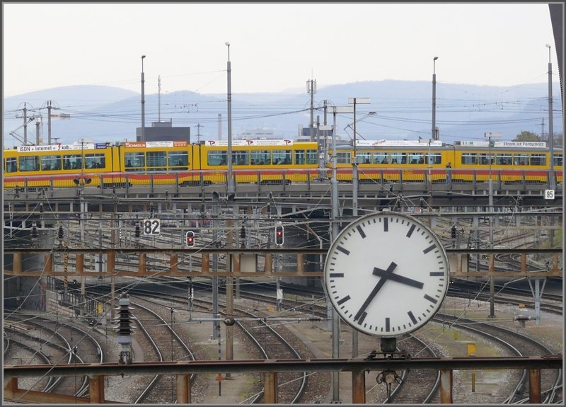 Unbersehbar trohnt diese riesige Bahnhofsuhr ber dem Gleisvorfeld des SBB Bahnhofs in Basel, leider ohne den klassischen roten Sekundenzeiger. Ein gemischter Tramzug der BVB berquert soeben die Geleise. (08.04.2008)