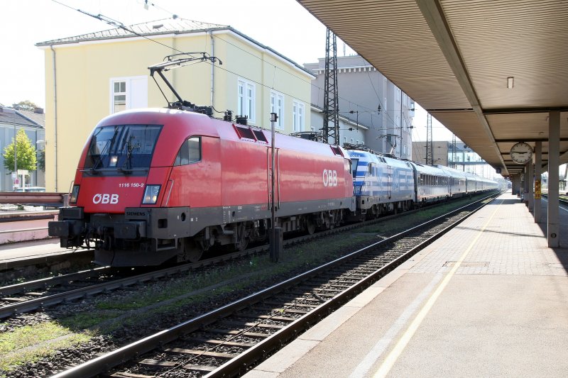 Verspteter EC 565  Tiroler Festspiele Erl  mit 1116 150 als Vorspann zur 1116 007  Griechenland  am 5.10.2008 im Bahmhof Wels.
Leider versperrte mir der zuvor ausfahrende IC 642  Ibis  die Sicht auf den einfahrenden EC, so konnte ich diesen Zug nur bei extremen Gegenlicht fotografieren und nicht - wie geplant - im Schatten des Bahnhofgebudes. 