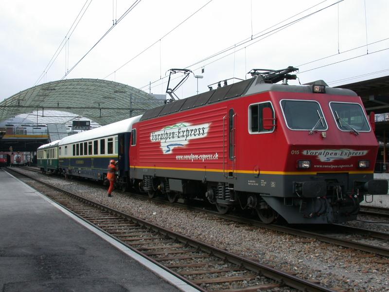 Voralpenexpresslok 015 der SOB (ex Re 4/4 IV der SBB) mit einem Sonderzug in Chur bestehend aus einem Speisewagen und einem Velowagen der Bodensee Toggenburg Bahn. (26.03.2004) Im Hintergrund ist die Halle der Postautostation zu sehen.