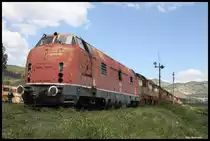 Albanien: Eine V 200.1 der DB zumindest gibt es hier am 18.5.2017 noch! HSH 2003 ex DB 200.124 steht fahrunfähig lädiert vor einem Lokzug, der ansonsten ausnahmslos aus tschechischen Cmellaks besteht, im Bahnhof Prrenjas nahe der mazedonischen Grenze. Es gibt dort zwar keinen Zugverkehr, aber der Bahnhof ist dennoch mit zwei Bahnern besetzt. Die netten Herren erklärten uns in aller Kürze den Verbleib der letzten V 200, die mit fünf an der Zahl 1989 nach Albanien kamen: Beim Umsturz mit der UCK kam es zu Übergriffen auf das Eisenbahn Gut.Zahlreiche Loks und Wagen wurden zerstört und später verschrottet. Die Lok HSH 2003 aber, die allein in Prrenjas stand, wurde dabei von dem Bahnhofsvorsteher und seinen Leuten heldenhaft verteidigt, so dass sie heute noch lediglich mit ein paar Einschüssen dort verblieben ist. Fahren wird sie sicher nicht mehr! Dazu fehlen zu viele Teile.