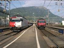Dieses Schauspiel wiederholt sich regelm��ig und t�glich jede Stunde in Arth Goldau. Links der Zug mit der Werbelok 460 090 ist der EC 109 Basel-Mailand, rechts der Zug mit der roten 460 115  Heidiland  ist IR 2261 Z�rich-Locarno. Dieser Zug f�hrt am Schluss auch einen Panoramawagen der 1. Klasse, wie fast alle IR&acute;s auf der Gotthardbahn. Im Hintergrund ist die Rigi, die K�nigin der Berge, zu erkennen. Die blauen Z�ge der (Arth-)Rigi-Bahn fahren immernoch auf dem Hochbahnsteig �ber den Gleisen 5-8 in Arth-Goldau ab. Auch dieses ist im Hintergrund zu erkennen.