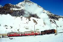 RhB - Dampfschneeschleuderextrazug 9462.2 f�r Graub�nden Tours von Alp Gr�m nach Ospizio Bernina am 28.02.1998 oberhalb Alp Gr�m mit Dampfschneeschleuder X d rot 9213 - Triebwagen ABe 4/4 I 30 + ABe 4/4 I 30. Hinweis: Triebwagen verkehren heute in gelber Lackierung, gescanntes Dia.
