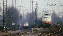 Paralleleinfahrt von 103 240-8 mit einem IC und eines Nahverkehrszuges mit führendem Steuerwagen um 1980 in den Bahnhof Köln-Deutz. Heute ist die im Hintergrund sichtbare Industriekulisse komplett verschwunden.