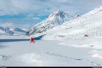 RhB Dampfschneeschleuderfahrt am 28. Januar 2018. <br>
Während der Helikopter der Schweizerischen Rettungsflugwacht Rega zur Landung ansetzt, wartet die Dampfschneeschleuder Xrotd 9213, geschoben vom Bernina-Krokodil Ge 4/4 182, beim Bahnübergang auf ihren Einsatz bei der dritten Schleuderdemo des Tages.