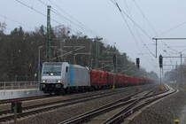 Im Schneeregen wartet die 186 271-3 der Railpool mit einem Holzzug am 03.02.2018 im Bahnhof Nassenheide..