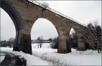 Soda-Viadukt und ein gut getarnter Zug im Schnee -

Das stillgelegte Primviadukt bei Rottweil mal in den Vordergrund geholt und den Zug nach hinten geschoben. Es war ganz knapp die Lok des IC2-Zuges da in die Lücke unterzubringen. Es gibt auch noch manche andere Standpunkte, wo Zug und Viadukt auf ein Bild zu bringen möglich sind. Nur darf man nicht erwarten, den Zug völlig unverdeckt ins Bild zu bekommen. Das ist meiner Meinung auch gar nicht nötig.

Im Sommer dürfte diese Motiv fast noch besser funktionieren, dann nur mit Führerhaus in der Lücke, oder die Front mit Schornstein einer Dampflok... Im Sommer verschwindet dann die störende Gewerbehalle im rechten Brückenbogen hinter Grün.

Leider ist die frühere Trasse im weiteren Verlauf nach rechts durch das Gewerbegebiet verbaut, eine Wiederaufbau der Strecke als Verbindung von Balingen und Rottweil ist dadurch wohl kaum mehr möglich.

19.02.2018 (M)