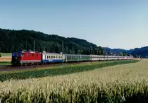 SBB: Re 4/4 II im Personenverkehr.
IC Brig-Basel mit einer nicht erkennbaren Re 4/4 II der ersten Serie auf der Fahrt bei Bollodingen im Juli 1999.
Besondere Beachtung gilt dem hinter der Lok eingereihten BLS-Klimaerprobungswagen oder auch  KAMELWAGEN  genannt wegen den beiden  Buckeln  auf dem Dach.
Damals standen auch noch die Eurofima-Wagen im Einsatz.
Foto: Walter Ruetsch  