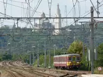 Triebzug 180 der SNCB/NMBS, von Liège-Guillemins kommend, fährt in den Bahnhof Angleur ein. Im Hintergrund erheben sich majestätisch die Eglise du Sacré-Coeur de Cointe und rechts daneben das Mémorial Interallié. Die Aufnahme entstand am 18/09/2010 vom Bahnsteig in Angleur. 
