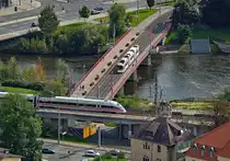 Von der Aussichtsterrasse des frei zugänglichen Jentowers hat man einen guten Überblick
über die thüringische Universitätsstadt Jena und auch deren recht interessanten Bahnanlagen.
Am 12.09.2010 war Jena noch an den Fernverkehr der DB angeschlossen, hier kommt gerade der
411 032  Wittenberge , ein ICE T, auf der Saalbahn im Paradies-Bahnhof zum stehen. Die
Straßenbahn nach Lobeda ist gerade unter den Bahnanlagen durchgefahren und überquert nun
die Saale in Richtung Burgau. Das Straßenbahnnetz in Jena wurde nach 1990 wesentlich
erweitert, der Anschluß der recht großen Stadtteile Lobeda West und Ost konnte vor der
Wende nicht realisiert werden und war nur mit -meist überfüllten- Bussen möglich. Dafür
hat Jena mit Inbetriebnahme der Schnellfahrstrecke Erfurt - Nürnberg seinen Fernverkehrs-
anschluss verloren, von einem  Verlegenheits-ICE  mal abgesehen. Auch der Bahnhof Paradies, der eher als Hp zu bezeichnen ist, macht eher einen kümmerlichen Eindruck, keinesfalls ein repräsentatives  Tor zur weiten Welt .