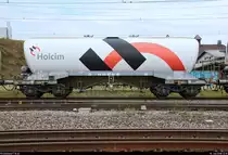 Blick auf einen Silowagen der Gattung  Uacns  (33 85 9326 103-9 CH-HOLCH) der LafargeHolcim Ltd., der in einem gemischten Gz mit Re 4/4 III 11360 (430 360-8) SBB eingereiht ist und den Bahnhof Pratteln (CH) in westlicher Richtung durchfährt.
Aufgenommen von der Güterstrasse.
[10.7.2018 | 12:15 Uhr]