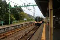 Serie 129, die neuen Triebzüge für die Präfektur Niigata (Japan, am Japanischen Meer). Einfahrt von Zug 129-105 im kleinen Dörfchen Izumozaki am Japanischen Meer. Man beachte den kleinen Blumenstrauss am Pfeiler des Bahnsteigdachs. 12.November 2018 