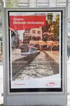 Plakatwerbung an der Haltestelle Stadttheater - Unsere fließende Verbindung.

Es gäbe auch eine Modellstraßenbahn mit Standardfarbe. Sie steht an der Freiburger Bächle. Die Freiburger Stadtverkehr VAG bestellt fünf neue Straßenbahnen der spanischen Hersteller CAF (Construcciones y Auxiliar de Ferrocarriles) und das typische Modell Urbos. Die Lieferung erfolgt im Sommer 2020. Dann lösen die alte Straßenbahnen der Typenbezeichnung GT8K ab. Die Aufnahme ist am 06.04.2019 entstanden. 
