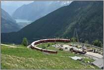 R1633 mit ABe 8/12 3503 fährt durch die Alp Grüm Kehre talwärts Richtung Lago di Poschiavo im Hintergrund und weiter bis Tirano (I). Der Seilbahnmast der Materialbahn dient zur Versorgung der Galeriebaustelle unterhalb Alp Grüm.  (19.06.2019)
