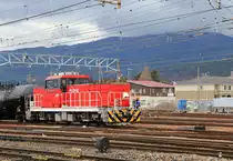Diesel-Hybridlokomotive HD-300 der japanischen Güterverkehrsgesellschaft JR Freight: Der Prototyp HD 300-901 erschien im März 2010, gefolgt von den Serienloks ab Juli 2011 (Nr. HD 300-1 bis 28, und für sehr kalte Gebiete HD 300-501 bis 503). Die teuren, 60 t schweren Loks mit der Achsfolge B - B werden in Rangierbahnhöfen mit hohem Verkehrsaufkommen eingesetzt, viele im Grossraum Tokyo. Im Bild ist Lok HD 300-10 mit der Ueberfuhr von schweren Tankwagenzügen in die Tanklager von Minami Matsumoto im japanischen Hochland beschäftigt. 21.März 2019  
