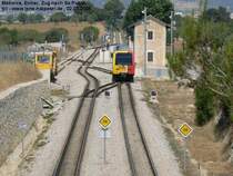 SFM, Bahnhof Enllac, �bersicht Gleisanlagen mit ausfahrendem Zug nach Sa Pobla. Das linke Streckengleis f�hrt nach Manacor. Links im Mittelgrund eine Plasser & Theurer Stopfmaschine. Foto: 02.07.2006