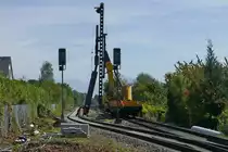 Bauarbeiten zur Elektrifizierung der Bodenseeg�rtelbahn, Streckenabschnitt Friedrichshafen - Lindau (|) - Zwei Arbeiter helfen tatkr�ftig, den Doppel-T-Tr�ger, die Gr�ndung f�r einen Oberleitungsmasten aus Beton, in die richtige Position zu schieben, damit die selbstfahrende Ramme diesen in den Boden vom Bahnhof Eriskirch rammen kann (20.09.2019).