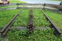 Dieses Gleisstück befindet sich am Museumslokschuppen in Rübeland und erinnert an die Zeit des Zahnstangenbetriebs bei der HBE (Harzbahn, heute Rübelandbahn), welcher Mitte der 20-er Jahre des letzten Jahrhunderts, nach Einführung der schweren preußischen T 20-Maschinen (Tierklasse)eingestellt wurde. Das Zahnstangensystem war Bauart Abt und dreilamellig ausgelegt, um die enormen Kräfte des Schwerlastverkehrs auf den extremen Steigungen aufnehmen zu können. Welche Kräfte da gewirkt haben müssen, läßt sich bei genauerem Hinsehen auch am Abnutzungsgrad der einzelnen Zähne erkennen! (Aufnahme vom 31.08.2019)